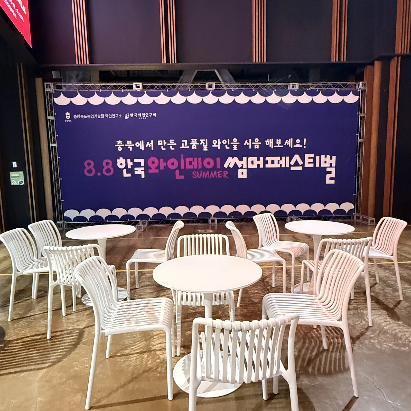 부스 옆 휴게 공간 — 흰 라탄 테이블과 의자