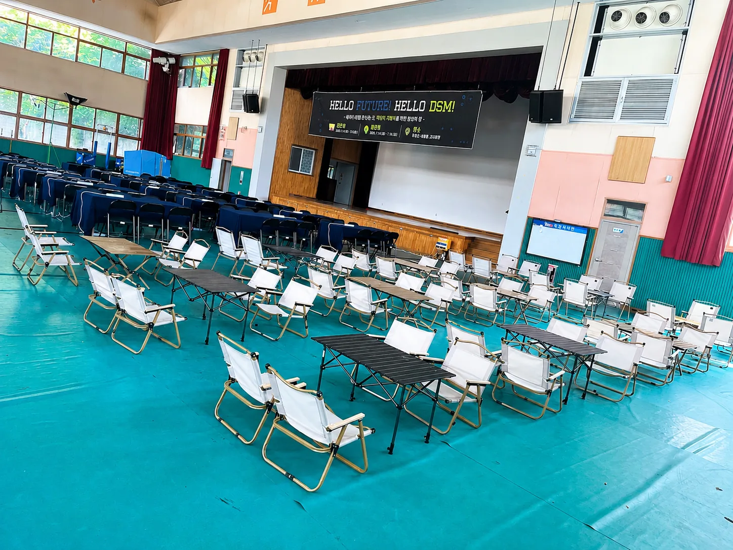 학교 체육관 — 캠핑의자와 낮은 테이블로 조별 자리를 만든 행사