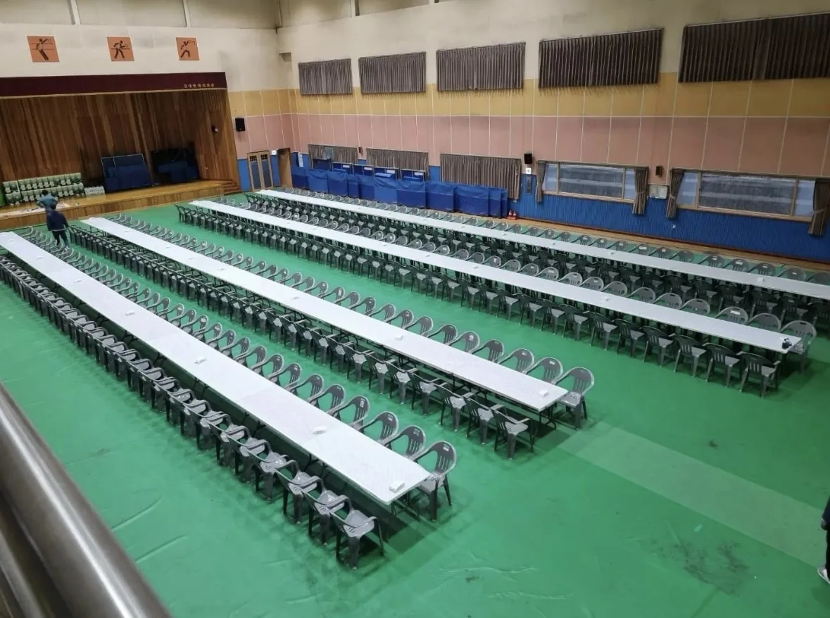 체육관 좌식 긴 테이블 세팅 — 학년 전체가 한 방향을 보는 배치