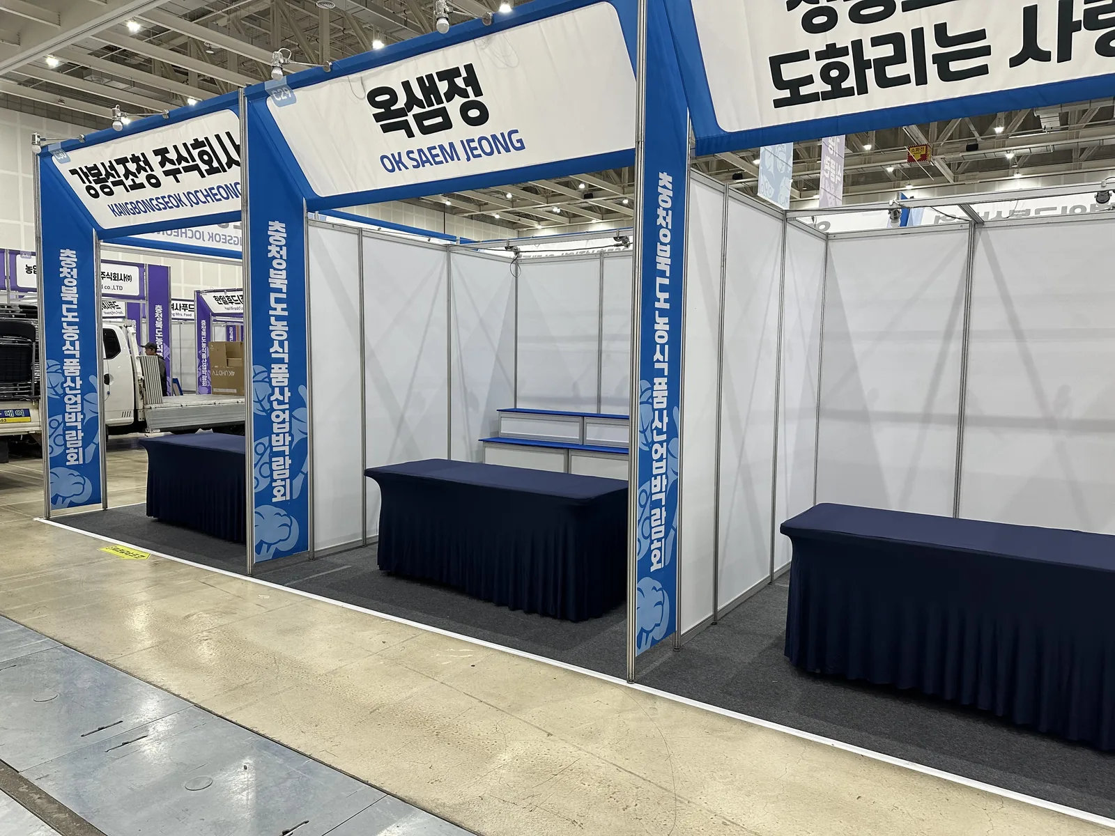 박람회 조립 부스 — 부스명 사인과 안내 테이블
