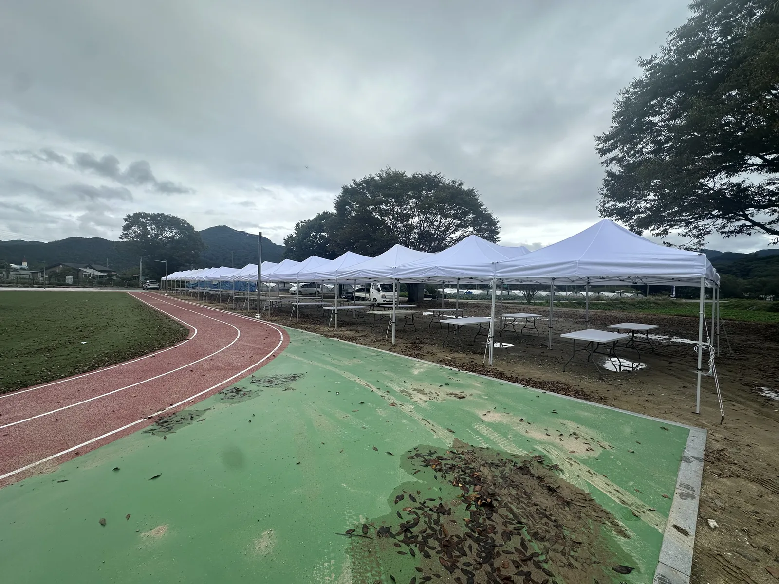 운동장 트랙 옆으로 캐노피 천막을 한 줄로 설치한 학교 운동회 현장