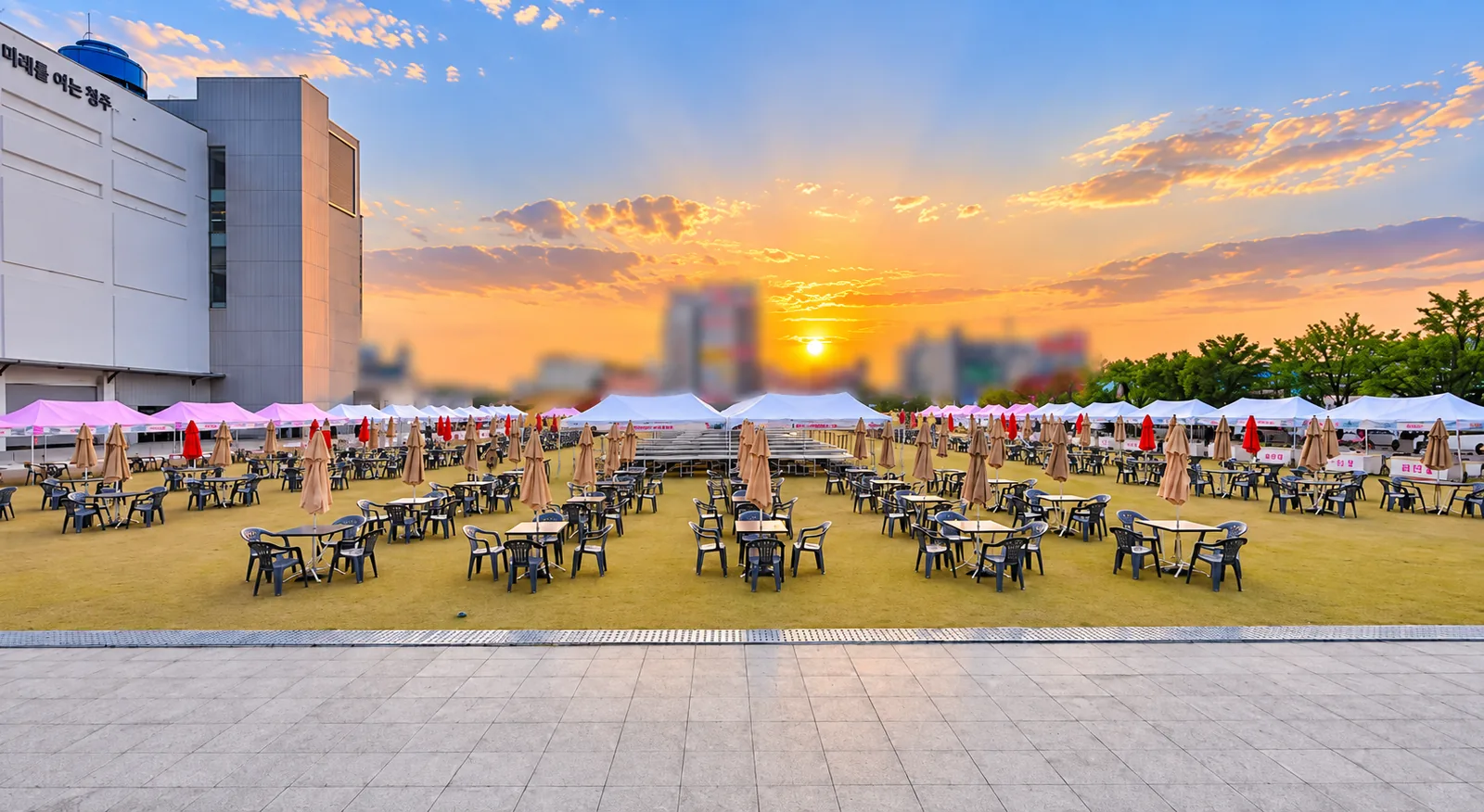해질 무렵 축제장 전경 — 부스 열과 관람 테이블